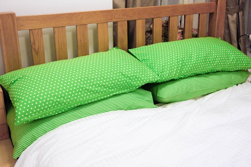 Pillows on a bed with green polkadot pillowcases